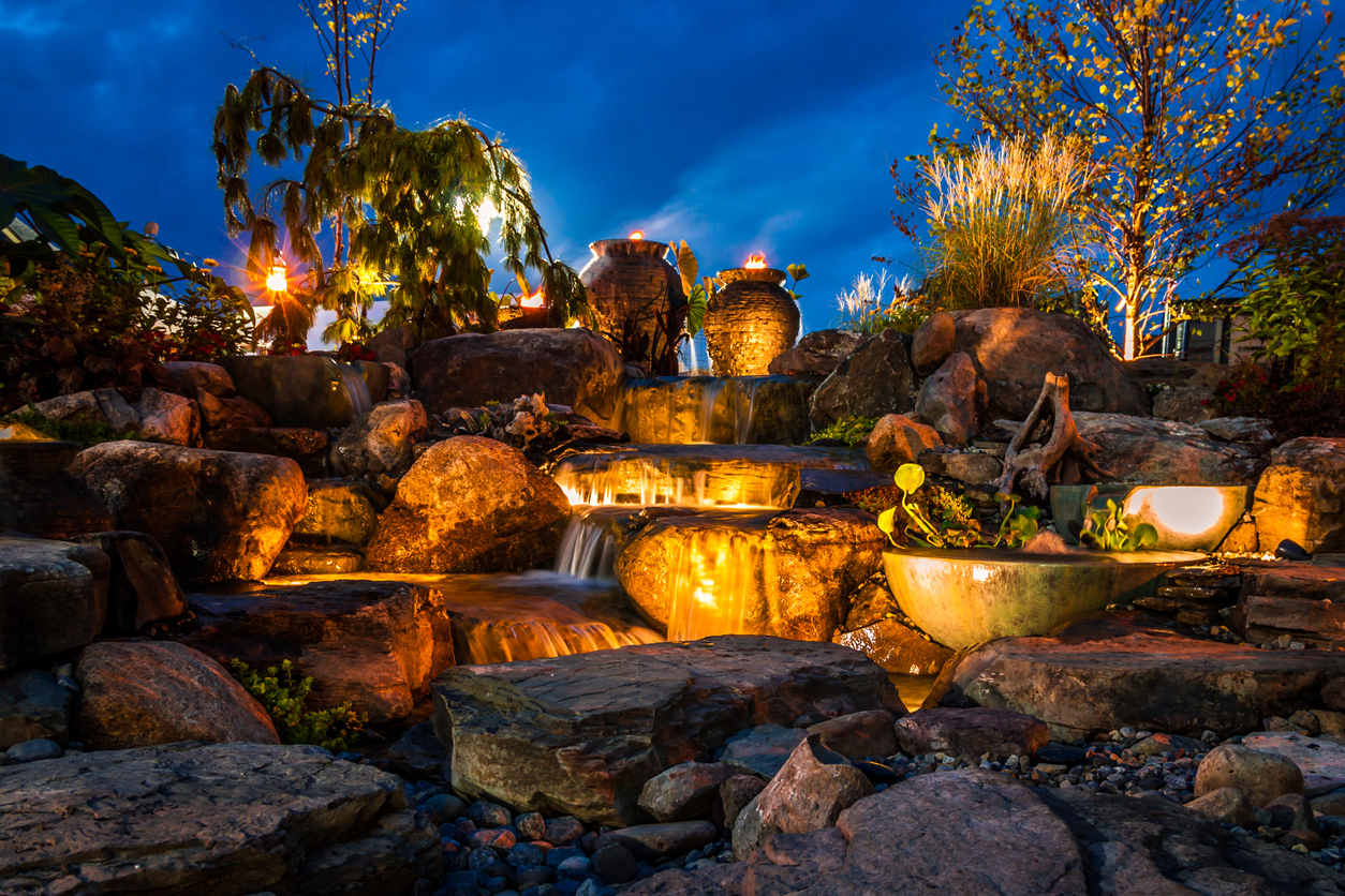 Waterfall fountain landscape at night with beautiful lights and tiki torches